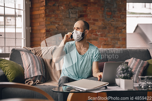 Image of Young man doing yoga at home while being quarantine and freelance working