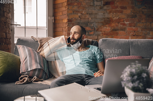 Image of Young man doing yoga at home while being quarantine and freelance working