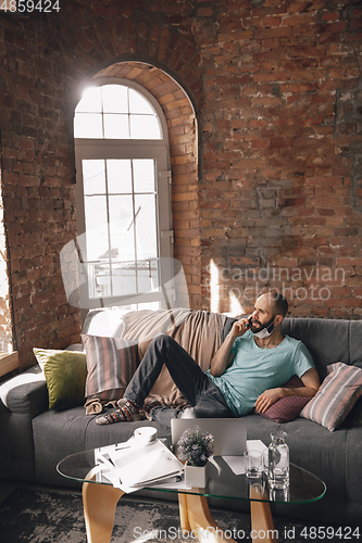 Image of Young man doing yoga at home while being quarantine and freelance working