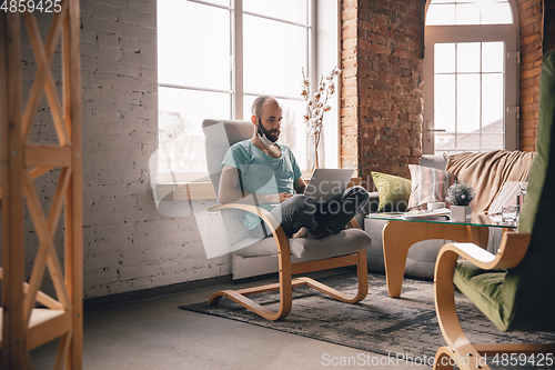 Image of Young man doing yoga at home while being quarantine and freelance working