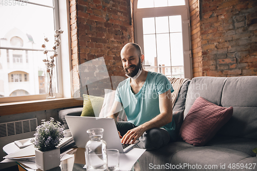 Image of Young man doing yoga at home while being quarantine and freelance working