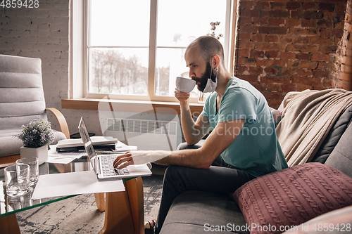 Image of Young man doing yoga at home while being quarantine and freelance working