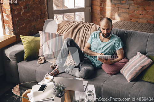 Image of Young man doing yoga at home while being quarantine and freelance working