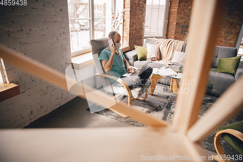 Image of Young man doing yoga at home while being quarantine and freelance working