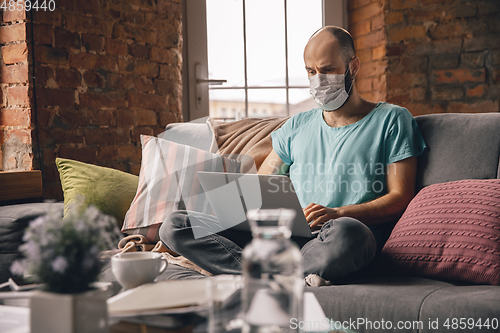 Image of Young man doing yoga at home while being quarantine and freelance working