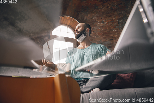 Image of Young man doing yoga at home while being quarantine and freelance working