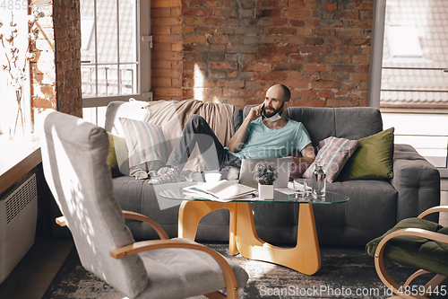 Image of Young man doing yoga at home while being quarantine and freelance working