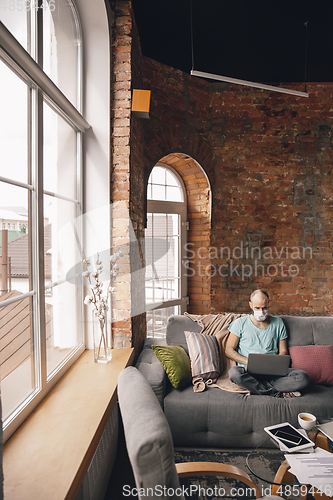 Image of Young man doing yoga at home while being quarantine and freelance working