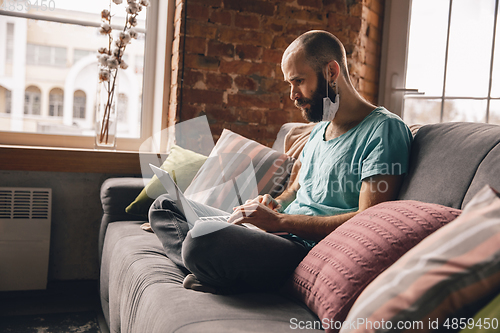 Image of Young man doing yoga at home while being quarantine and freelance working