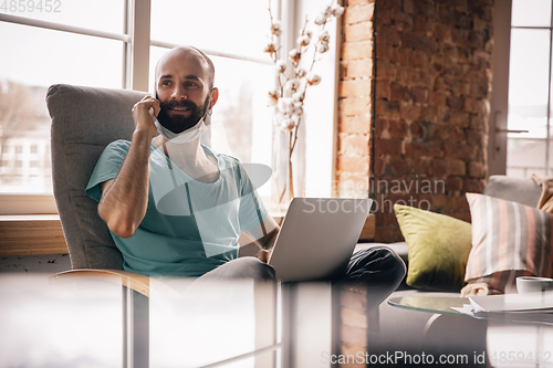 Image of Young man doing yoga at home while being quarantine and freelance working