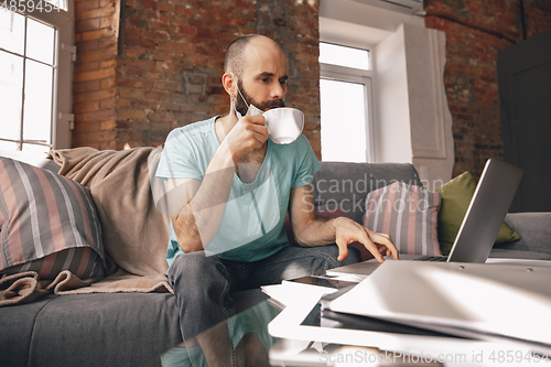 Image of Young man doing yoga at home while being quarantine and freelance working