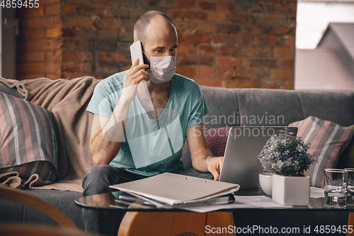 Image of Young man doing yoga at home while being quarantine and freelance working