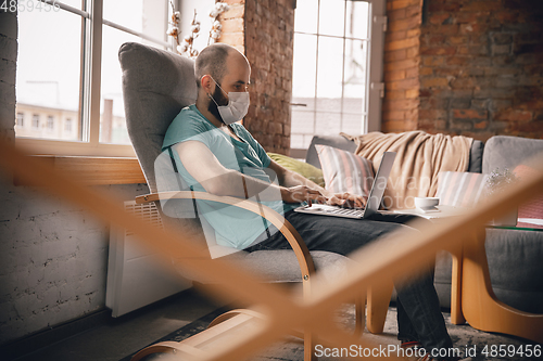 Image of Young man doing yoga at home while being quarantine and freelance working