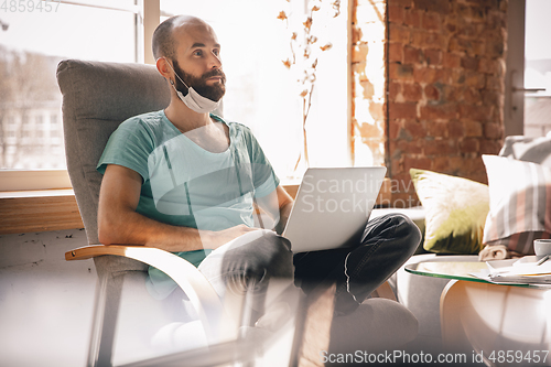 Image of Young man doing yoga at home while being quarantine and freelance working