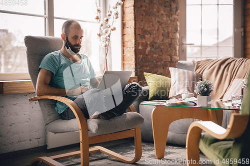 Image of Young man doing yoga at home while being quarantine and freelance working