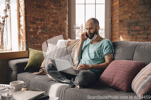 Image of Young man doing yoga at home while being quarantine and freelance working