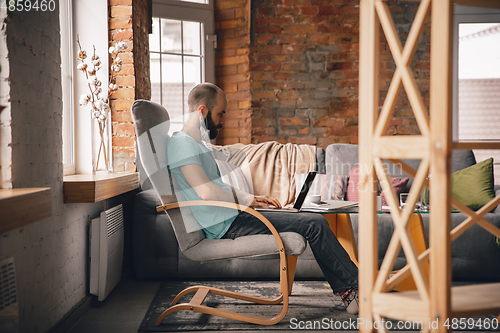 Image of Young man doing yoga at home while being quarantine and freelance working