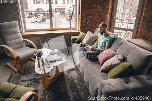 Image of Young man doing yoga at home while being quarantine and freelance working