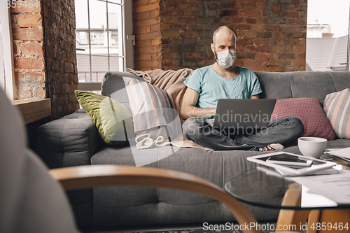 Image of Young man doing yoga at home while being quarantine and freelance working