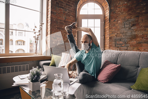 Image of Young man doing yoga at home while being quarantine and freelance working