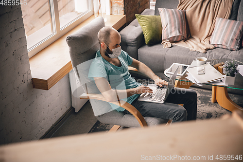 Image of Young man doing yoga at home while being quarantine and freelance working