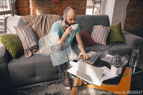 Image of Young man doing yoga at home while being quarantine and freelance working