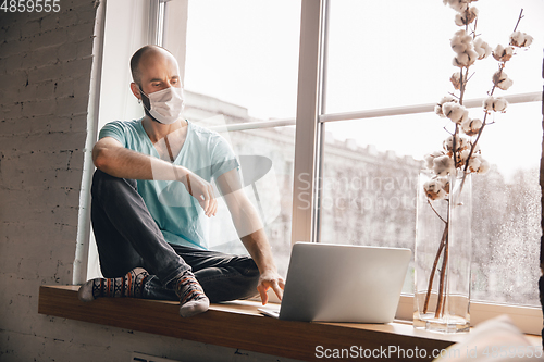Image of Young man doing yoga at home while being quarantine and freelance working
