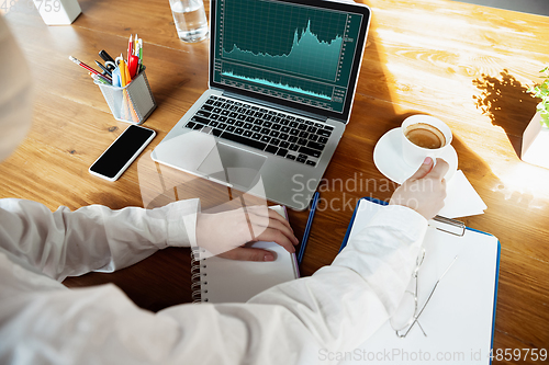 Image of Woman working in office alone during coronavirus or COVID-19 quarantine, wearing face mask