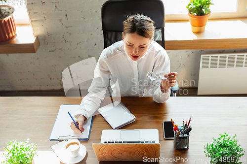 Image of Woman working in office alone during coronavirus or COVID-19 quarantine, wearing face mask