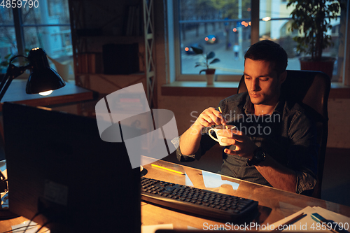 Image of Man working in office alone during coronavirus or COVID-19 quarantine, staying to late night