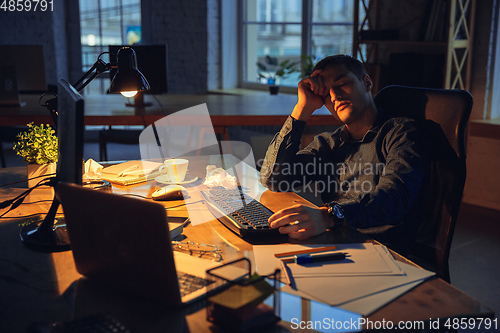 Image of Man working in office alone during coronavirus or COVID-19 quarantine, staying to late night