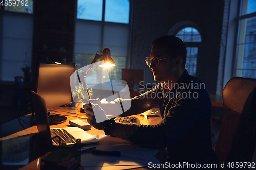 Image of Man working in office alone during coronavirus or COVID-19 quarantine, staying to late night