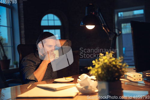 Image of Man working in office alone during coronavirus or COVID-19 quarantine, staying to late night