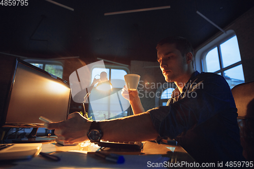 Image of Man working in office alone during coronavirus or COVID-19 quarantine, staying to late night