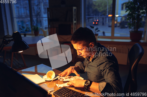 Image of Man working in office alone during coronavirus or COVID-19 quarantine, staying to late night