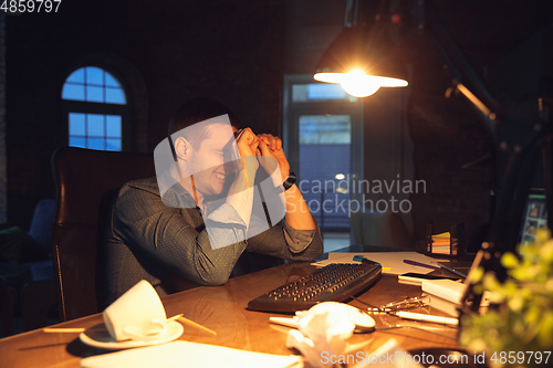 Image of Man working in office alone during coronavirus or COVID-19 quarantine, staying to late night