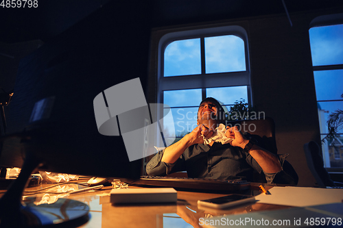 Image of Man working in office alone during coronavirus or COVID-19 quarantine, staying to late night