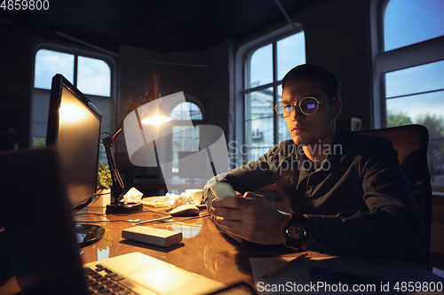 Image of Man working in office alone during coronavirus or COVID-19 quarantine, staying to late night