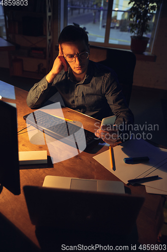 Image of Man working in office alone during coronavirus or COVID-19 quarantine, staying to late night