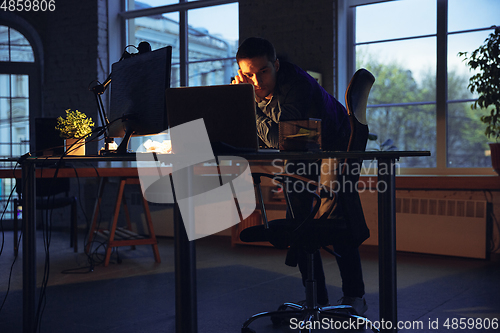 Image of Man working in office alone during coronavirus or COVID-19 quarantine, staying to late night