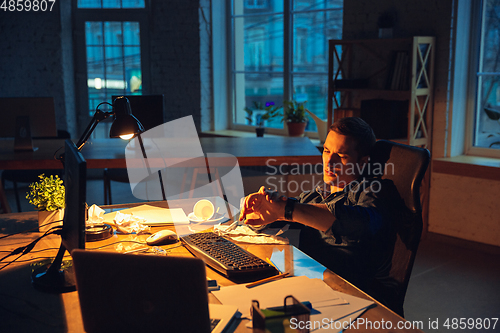 Image of Man working in office alone during coronavirus or COVID-19 quarantine, staying to late night