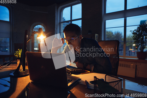 Image of Man working in office alone during coronavirus or COVID-19 quarantine, staying to late night