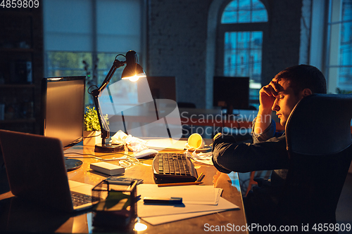 Image of Man working in office alone during coronavirus or COVID-19 quarantine, staying to late night