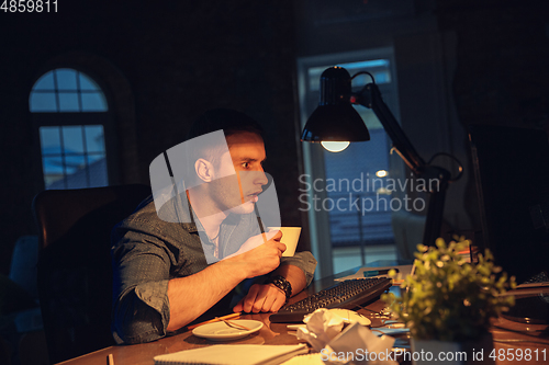 Image of Man working in office alone during coronavirus or COVID-19 quarantine, staying to late night