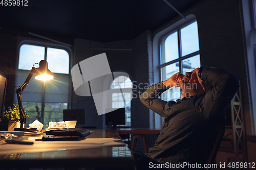 Image of Man working in office alone during coronavirus or COVID-19 quarantine, staying to late night