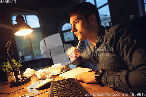 Image of Man working in office alone during coronavirus or COVID-19 quarantine, staying to late night