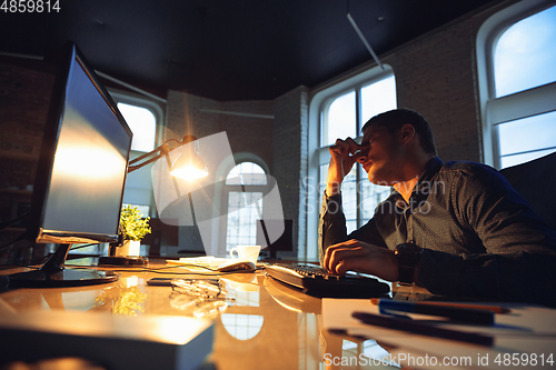 Image of Man working in office alone during coronavirus or COVID-19 quarantine, staying to late night