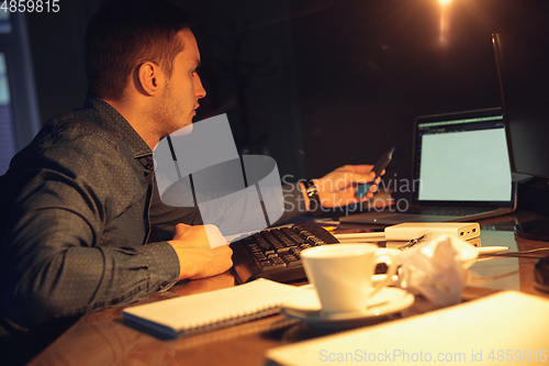 Image of Man working in office alone during coronavirus or COVID-19 quarantine, staying to late night