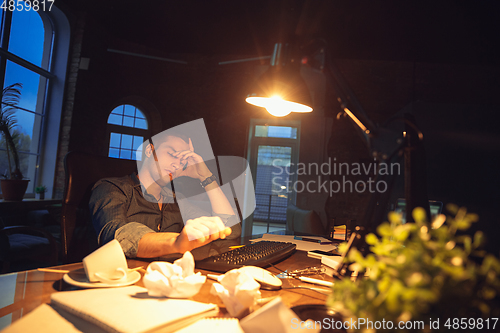 Image of Man working in office alone during coronavirus or COVID-19 quarantine, staying to late night