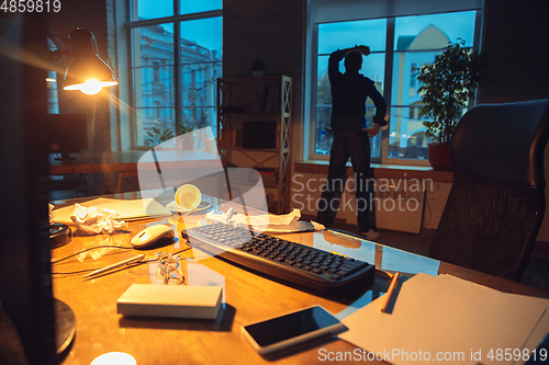 Image of Man working in office alone during coronavirus or COVID-19 quarantine, staying to late night